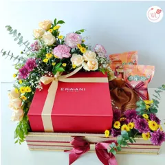 A custom wedding hamper designed with grandeur and grace. This gift features a large red box from Ekani, surrounded by a vibrant mix of roses, carnations, and other seasonal flowers.