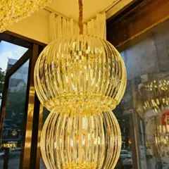 This two-tiered chandelier features vertical crystal rods that create a beautiful, ribbed texture. The warm, golden light filters through the crystals, producing a sophisticated glow ideal for a luxurious living or dining room.