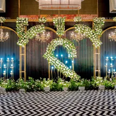 A bold statement for a modern Sangeet. This setup features a dramatic black and white chevron floor, custom floral monograms, and opulent chandeliers, proving that indoor ballroom events can be truly iconic.