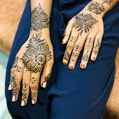 A modern Arabic henna design perfect for a party. The pattern is focused on the back of the hand, with bold floral motifs and delicate dots on the fingers.