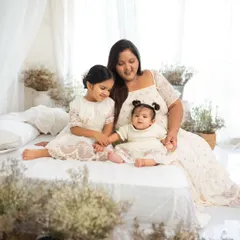 A mother sharing a sweet moment with her two daughters. The natural light from the studio window creates a soft and flattering glow.