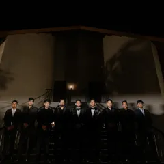 A moody, dramatic group portrait of the groom and his groomsmen, lined up on a staircase at night.