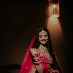 A serene bridal portrait. Using dramatic, focused lighting, I highlighted the bride's gentle smile and the rich colors of her red lehenga, creating a moody and artistic shot.