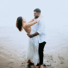 A romantic and playful dip on the beach. This pose is full of laughter and connection, showing a couple completely lost in their own world.