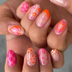 Why choose one design when you can have them all? This playful and creative manicure features a different design on each nail, including checkerboard patterns, florals, swirls, and hearts in a vibrant pink and orange color scheme.