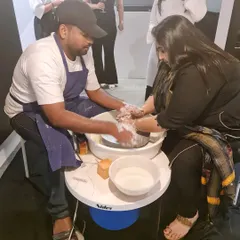 An instructor provides hands-on assistance to a participant on the pottery wheel during our special event. We ensure everyone gets the guidance they need to create their piece.