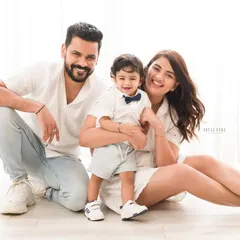 A picture-perfect family of three. Their coordinated white outfits and bright smiles make for a classic and joyful family portrait.