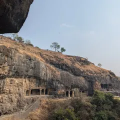 A view of the rock-cut caves from a distance. The way these structures are integrated into the natural cliffside is a lesson in harmony between nature and human creation.