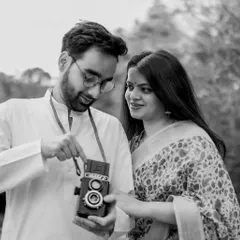 A sweet moment of shared discovery. The groom shows the bride how the vintage twin-lens reflex camera works, creating an engaging and authentic portrait that tells a story.
