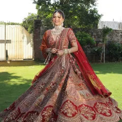 A full-length shot of a bride looking radiant in our intricately embroidered red and orange lehenga. The perfect outfit for a grand outdoor wedding.