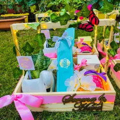 I designed this whimsical baby announcement hamper in a personalized wooden crate featuring the baby's name in a beautiful cutout. The 'Butterfly Garden' theme is brought to life with fairy lights, lush greenery, and carefully selected gifts like a swan-shaped planter and rose-flavored white tea.