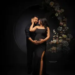 A romantic couple's portrait with a beautiful floral hoop. The dark, moody lighting creates an intimate and sophisticated atmosphere.