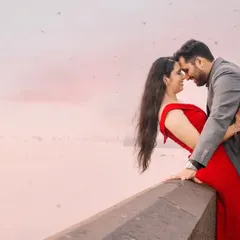 A romantic pre-wedding photo captured at Mumbai's Marine Drive. The hazy, pink sky and the sea create a dreamy atmosphere for this intimate embrace.