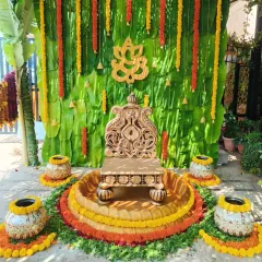 For this outdoor Haldi ceremony, I created an authentic and traditional atmosphere using a backdrop of fresh banana leaves and marigold flower garlands. The setup is centered around an ornate wooden chowki, complemented by decorated earthen pots, perfect for traditional pre-wedding rituals.