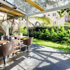 The styling stations at Enrich Salon are placed in a glass-enclosed pavilion, offering serene views of the surrounding greenery. The design ensures that even air-conditioned indoor spaces are flooded with diffused natural light filtered through the onsite trees.