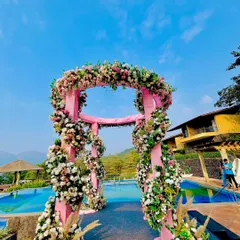 A closer view of the poolside floral mandap, highlighting the lush flower arrangements and the beautiful contrast with the bright blue sky and water.