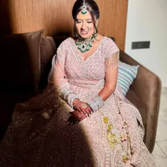A beautiful, serene moment of the bride. The soft lighting highlights her glowing makeup and the intricate details of her lehenga.