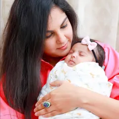 A mother's loving gaze as she holds her sleeping newborn. Our lifestyle sessions are about capturing the natural bond and emotion in the comfort of your own home.