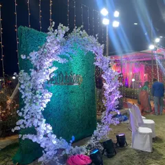 Another view of a circular photo arch, this time placed on a greenery wall. The white blossoms are lit with purple uplighting, creating a dramatic effect for evening events.