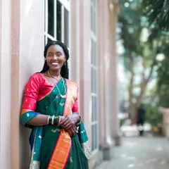 A beautiful portrait of a bride in a traditional green and red silk saree, her smile lighting up the frame.