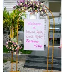 An elegant welcome stand for a twin's birthday party. The golden arch adorned with fresh flowers creates a beautiful and sophisticated entrance for your guests.