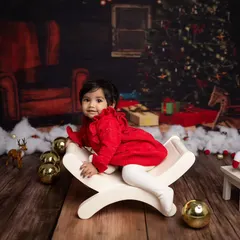 A sweet pose on a white bench amidst a festive Christmas scene with a snowman and golden ornaments.