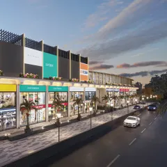 A view of the mall's high-street-style elevation at dusk. The design features illuminated storefronts and a landscaped walkway to create a vibrant pedestrian experience.