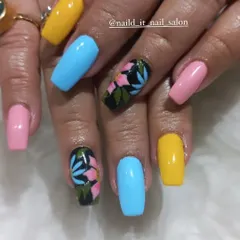A vibrant mix-and-match set for color lovers. Bright yellow, blue, and pink nails are paired with accent nails featuring hand-painted tropical flowers on a contrasting black background.
