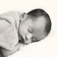 The simplicity of a sleeping baby in a soft, knitted wrap is timeless. This classic black and white portrait focuses on the peaceful expression and delicate features of your newborn.