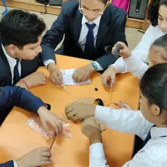 A close-up view of students working together to build a small robotic vehicle. This exercise teaches precision, teamwork, and an understanding of how individual components form a functional system.