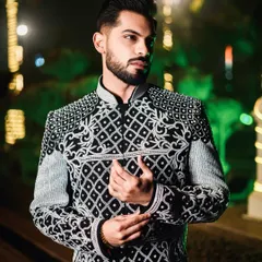 This shot captures the sharp tailoring and detailed craftsmanship of the black and ivory Indo-Western jacket. The geometric and paisley patterns are all done by hand, showcasing unparalleled skill.