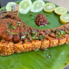 A closer look at our Crispy Pork Ribs, showing the crunchy, scored skin and tender meat beneath. We season it with authentic Naga flavors and serve it with a simple garnish of fresh lime and cucumber.