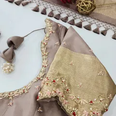 I love playing with different textures and colors. This elegant beige blouse features a sleeve made with a traditional gold silk border. The body of the blouse is adorned with delicate floral embroidery using pink and red threads, pearls, and stones for a subtle pop of color.