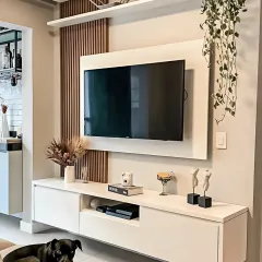 A minimalist floating TV unit in crisp white, accented with vertical wood slats for texture. This design keeps the living area feeling open and uncluttered, with a hanging plant adding a touch of natural softness.