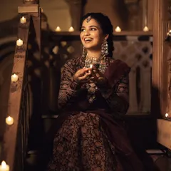 A joyful moment from our Deepawali editorial. The model's makeup features a soft, traditional look with a bindi, defined eyes, and a natural lip color that harmonizes with the intricate Kalamkari lehenga and antique jewelry.
