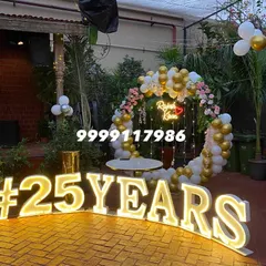 A different milestone anniversary setup with a circular backdrop, fairy lights, and large '#25YEARS' marquee letters on a brick patio.
