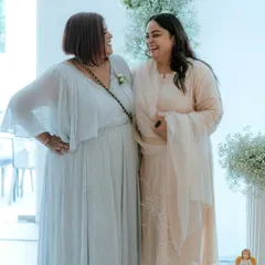 Two generations sharing a laugh in their custom pastel outfits. The flowing georgette gown and the elegant salwar suit were designed to complement each other beautifully.