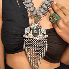 A bold, layered look featuring two of our oxidized silver necklaces. The top piece has paisley motifs, while the bottom one is a statement pendant with a large central stone and silver mesh.