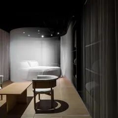 The retail space is designed as a series of interconnected zones. Here, a quiet discussion area is positioned to overlook the veiled product pods, creating a layered experience where clients can consult and reflect within the immersive Japandi-inspired interior.