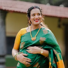 The joy of motherhood shines so brightly. This expecting mother looks radiant in a green and yellow silk saree, captured during a beautiful outdoor traditional maternity shoot.