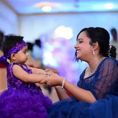 Capturing a beautiful moment between a mother and daughter. The daughter wears a custom vibrant purple party dress with voluminous ruffles, designed for celebration. I pride myself on creating outfits that bring joy and receive wonderful feedback on fit and timely delivery.