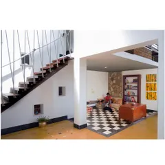 The interior features a sunken lounge area with a checkerboard floor, creating a cozy, defined space for gathering. The minimalist staircase with its thin steel balusters keeps the space feeling open and light.