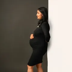 A beautiful side profile in our classic black turtleneck maternity dress, perfectly highlighting the baby bump.