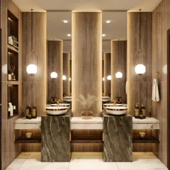 This luxurious powder room features two statement vessel sinks on a marble countertop. We used dark green marble pedestals and a wood-paneled wall with dramatic backlighting to create an opulent and symmetrical design.