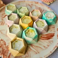 A collection of my hexagon-shaped candles ready for an order. I add gold foil flakes for a little extra sparkle. You can choose from six different fragrances, from mild vanilla to bold rose.