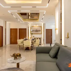 A closer look at the open-plan living space, highlighting the seamless flow into the dining area. Notice the custom wall paneling, statement art, and elegant furniture that combine to create a cohesive and inviting environment for family and guests.