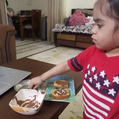 A student carefully adds sprinkles to her chocolate rusk creation. Activities like this are a great sensory experience and help develop coordination and focus.