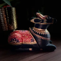 The dramatic lighting on this black and gold Nandi highlights the intricate spiral patterns and delicate dot work on its body. Each detail is painted with care to create a sense of richness and depth.