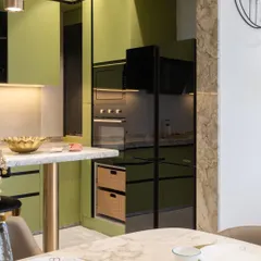 This view shows the tall unit housing the built-in oven and microwave, seamlessly integrated with the sage green cabinetry. The design maximizes vertical space for storage and appliances.