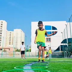A young boy carefully navigates an agility ladder. These drills are excellent for developing footwork, speed, and concentration in our budding football players.